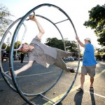 Peter Wm Wagner teaches Chris Jones how to ride his German gymnastics wheel Sunday at the Cool Davis Festival in 2011