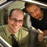 two men in a car giving thumbs up through the sunroof