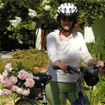 dorothy standing in garden holding bike with roses in basket
