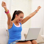 girl raising arms in happiness with laptop in front of her