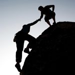 two climbers on a rock helping each other