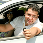 man and woman in new car holding key in air