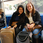 two girls on a bus with suitcases