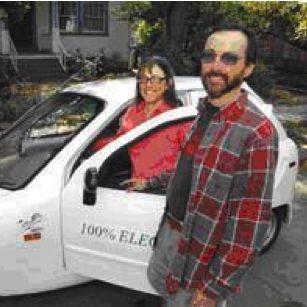 david and susan standing by their electric car